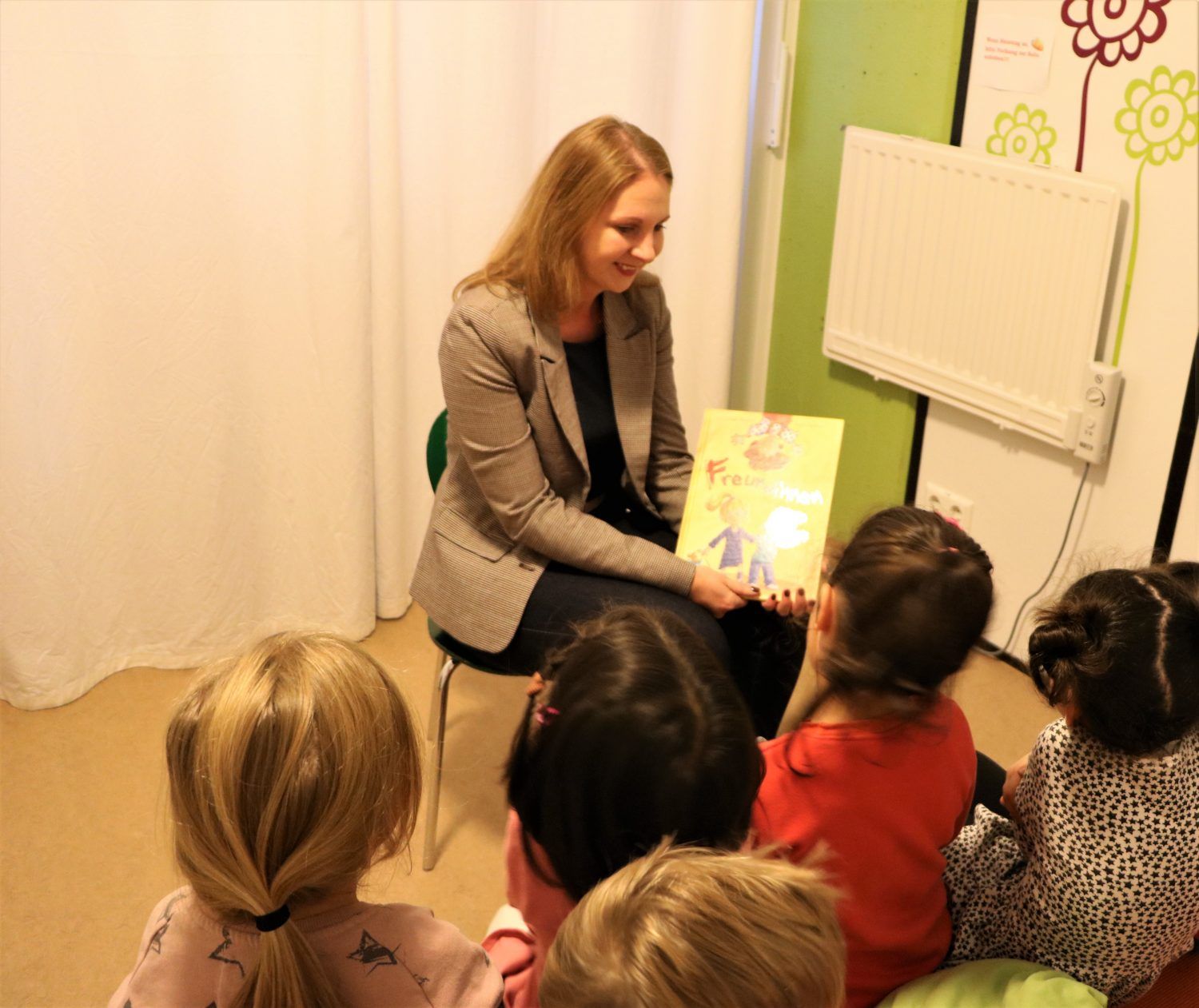 Sandra Boser schaut mit Kindergartenkindern ein Bilderbuch an